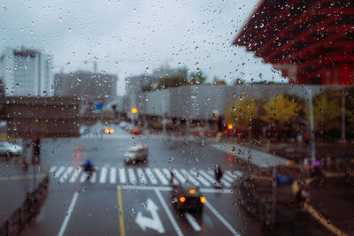 Cars on road seen through wet glass window in rainy season