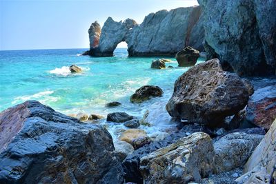 Rocks on shore by sea against sky