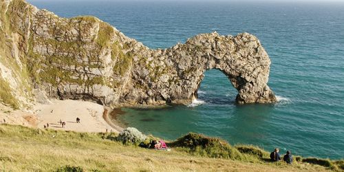 Scenic view of cliff by sea against sky