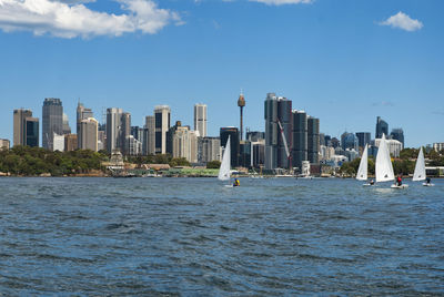 Sea by modern buildings in city against sky