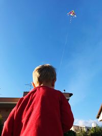 Rear view of girl standing against blue sky