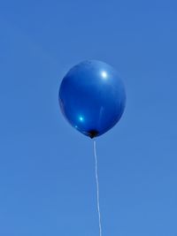 Low angle view of blue helium balloon against clear sky