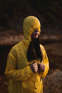 Midsection of woman with yellow umbrella standing on land