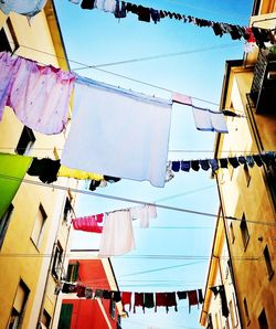 Low angle view of clothes hanging on building against sky