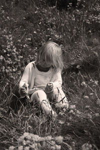 Rear view of girl sitting on field