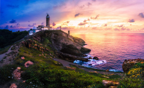 Scenic view of sea and buildings against sky during sunset