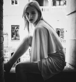 Portrait of young woman sitting in city