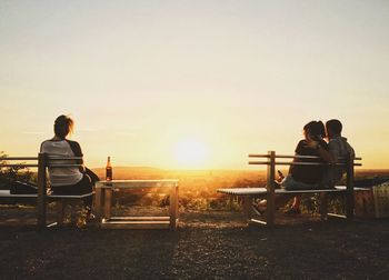 Rear view of couple sitting on chair against clear sky