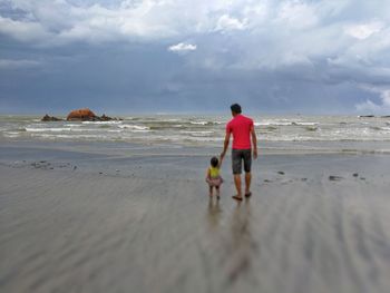 Rear view of man on beach against sky