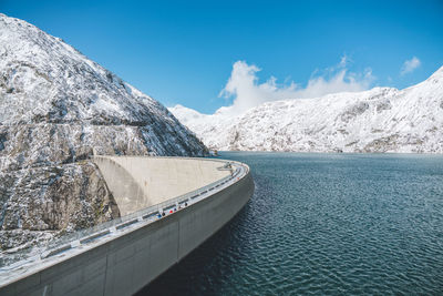 Scenic view of dam and mountains against sky