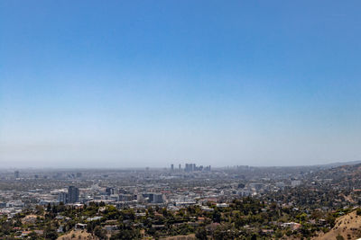Aerial view of buildings in city against clear blue sky