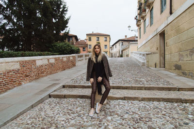 Woman sitting on bollard in city