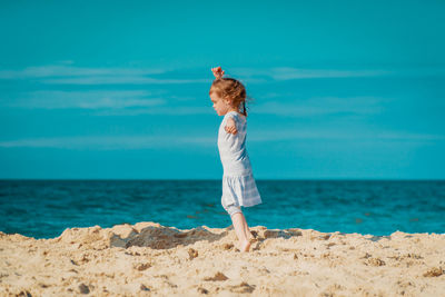 Woman standing on beach by sea against sky