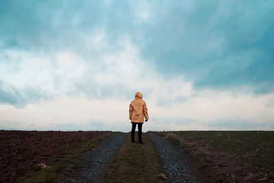 Rear view of man standing against cloudy sky