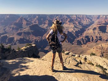 Full length of woman standing on rock against sky