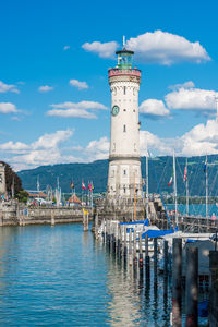 Lighthouse amidst sea and buildings against sky