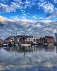 Buildings by river against sky