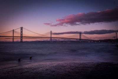 View of suspension bridge in city at sunset
