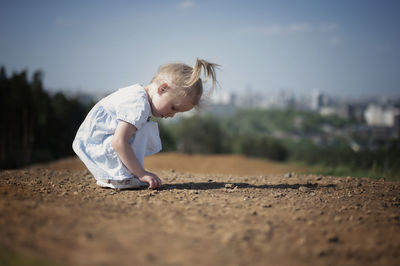 Side view of girl playing on land against sky