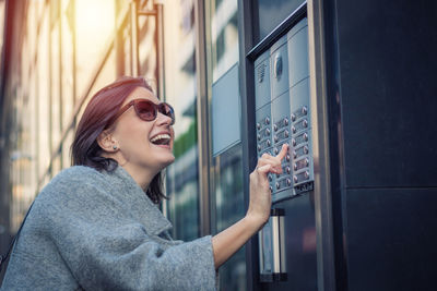 Smiling woman using intercom in city