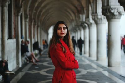 Portrait of a beautiful young woman standing in colonnade