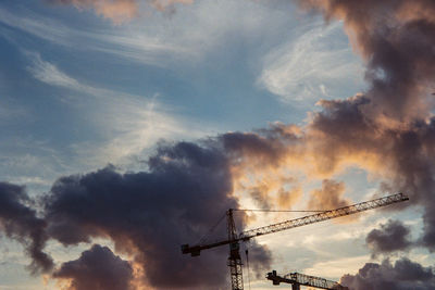 Low angle view of silhouette cranes against sky during sunset