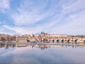 Arch bridge over river by buildings against sky