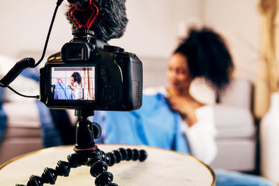 Camera recording woman holding dress while sitting on rug at home