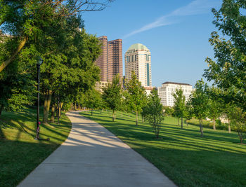 Road amidst trees and buildings against sky