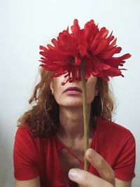 Close-up of woman with red flower against white background