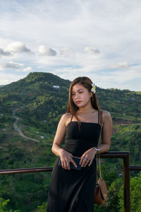 Young woman standing on mountain against sky