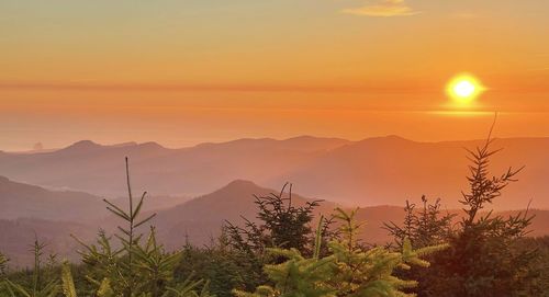 Scenic view of silhouette mountains against orange sky