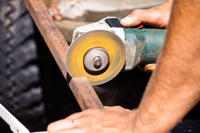 Close-up of hands cutting metal with angle grinder