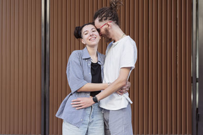 Couple embracing each other standing in front of wall