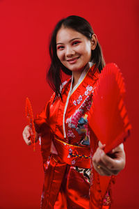 Portrait of young woman standing against yellow background