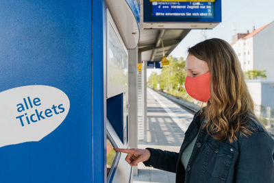 Woman using ticket machine at railway station