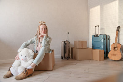 Portrait of young woman sitting in cardboard box at home