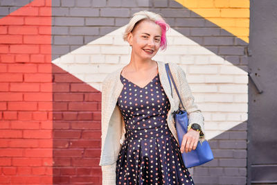 Smiling young woman standing against brick wall