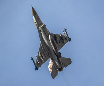 Low angle view of airplane flying against clear blue sky