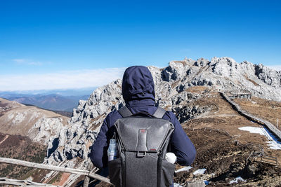 Rear view of person on snowcapped mountain against sky