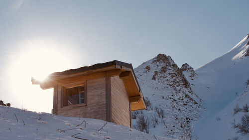 Low angle view of snow covered cabin against sky