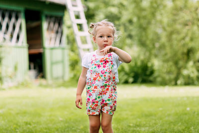 A little girl is playing in the garden, blowing on her hand. childhood, summer time, outdoor games