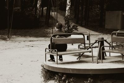 Rear view of man sitting on boat moored in forest