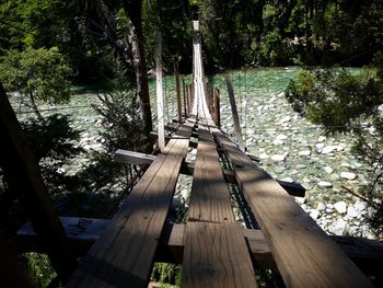 Wooden footbridge over river in forest