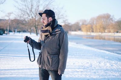 Man holding camera on street in snow