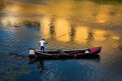 Man standing in boat on lake