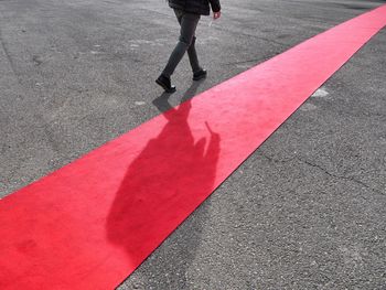 Low section of man walking by red carpet on road