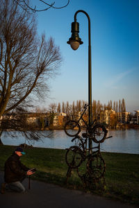 Man sitting on street light against sky