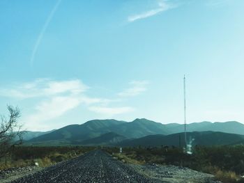 Road by mountains against sky