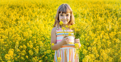 Portrait of cute girl holding flowers on field